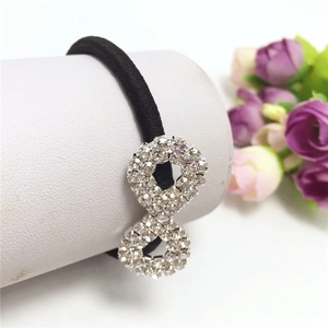 Close-up of black elastic hair tie featuring a sparkling rhinestone infinity charm decoration