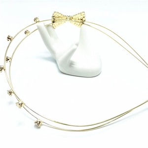 Détail d'un serre-tête doré à double rangée avec strass et un nœud métallique délicat
