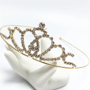 Elegante tiara dorata a forma di cuore con strass scintillanti su espositore a mano