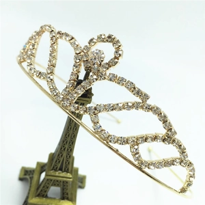 Detail view of a sparkling gold rhinestone crown displayed on a miniature tower stand