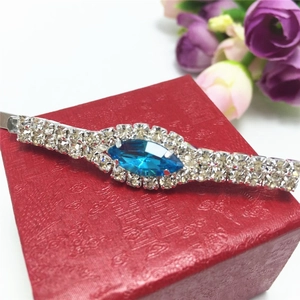 Detailed macro view of silver hair clip with blue gemstone and rows of rhinestones