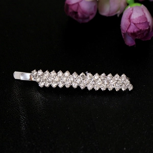 Détail d'une pince à cheveux argentée ornée de quatre rangées de strass brillants sur fond noir