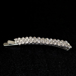 Détail de la barrette argentée avec trois rangées de strass clairs sur fond noir