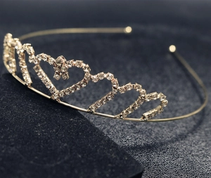 Close-up of golden rhinestone crown headband with heart patterns and sparkling stars