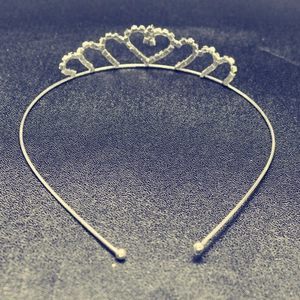 Detail view of a silver-colored heart-shaped tiara featuring sparkling white rhinestones