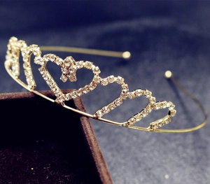 Detailed side view of a gold heart crown headband with sparkling rhinestones and bow