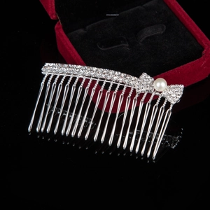Detail of silver alloy hair comb with sparkling rhinestones, pearls and bow design