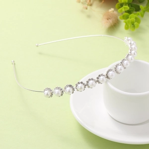 Silver pearl headband with rhinestones leaning on a coffee cup in a soft setting
