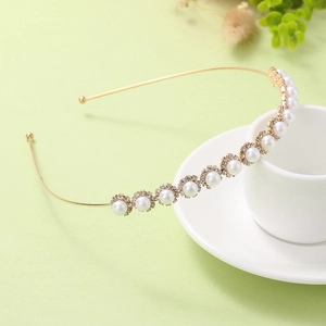 Detailed close-up of gold metal headband with pearl floral clusters on white cup