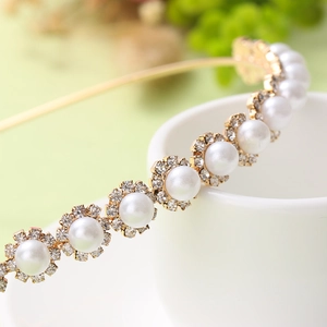 Detailed macro view of elegant gold metal headband with white pearls and sparkling rhinestones