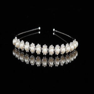 Elegant silver pearl headband with rhinestone accents on a black reflective surface