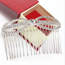 Detail of a silver bridal hair comb with rhinestone bow tie on a red gift box