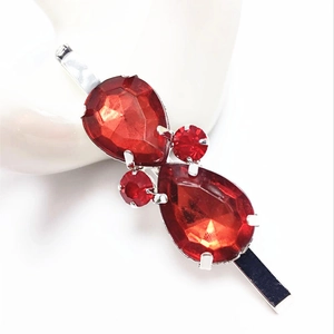 Détail d'une barrette argentée ornée de strass rouges étincelants en forme de poire