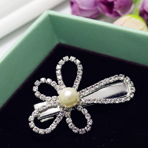 Macro detail of silver floral hair clip with crystal rhinestones and white pearl inlay
