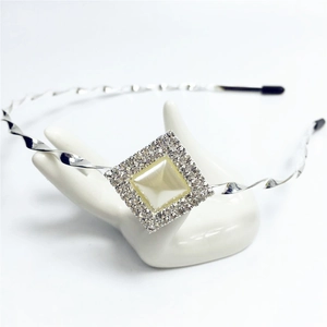 Elegant silver rhinestone headband with rhombus pearl pendant on ceramic display