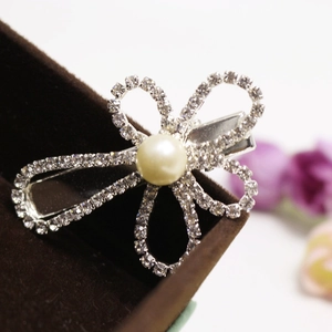Elegant silver hair clip featuring a rhinestone flower and a pearl on a velvet display
