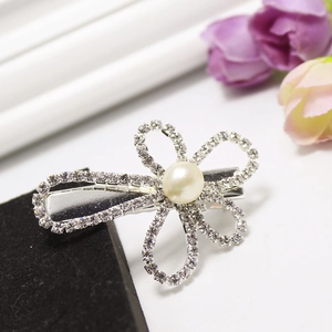 Detail of silver flower hair clip with sparkling rhinestones and a white faux pearl center