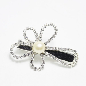 Detailed macro view of a silver floral hair clip with white rhinestones and a pearl center