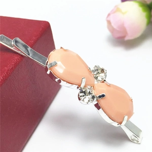 Détail d'une barrette argentée avec des gemmes pêche et des strass étincelants