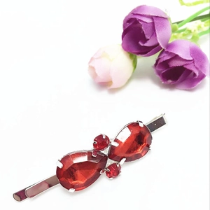 Barrette élégante avec cristaux rouges en goutte et base en métal sur fond minimaliste