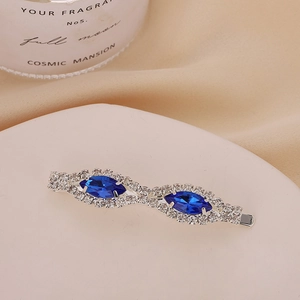 Détail d'une barrette vintage en argent avec strass bleu marine sur tissu beige doux