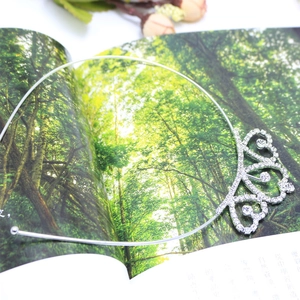 Detailed view of silver crystal heart necklace pendant on a magazine background