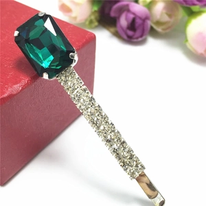 Détail d'une barrette dorée ornée d'un zircon émeraude et de cristaux scintillants