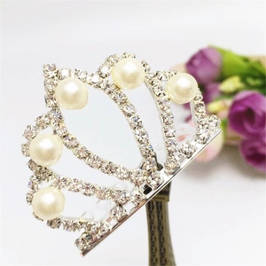 Dettaglio di fermaglio a corona in argento con perle finte e strass bianchi lucidi