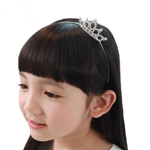 Detail view of a child wearing a silver tiara headband with sparkling white rhinestones