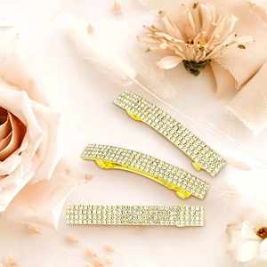 Dettaglio di fermagli per capelli dorati con strass su elegante sfondo floreale rosa