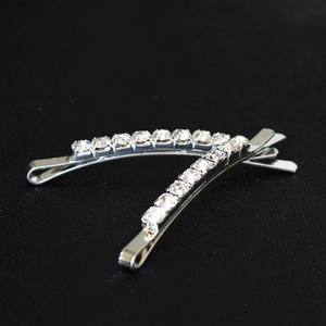 Détail macro de deux barrettes argentées avec strass brillants sur fond de cuir noir
