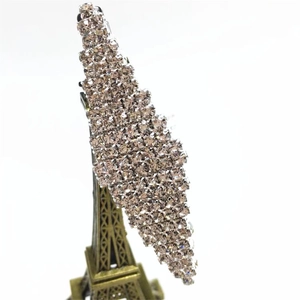 Detailed close-up of leaf-shaped hair clip with champagne rhinestones on metal pin