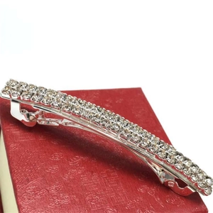 Dettaglio del fermaglio per capelli argento con tre file di strass su scatola rossa