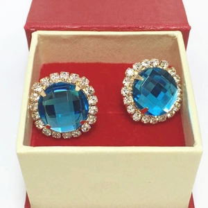 Close-up of blue crystal flower earrings with white rhinestones in a gift box