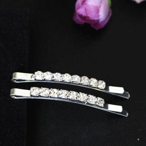 Vue macro de deux barrettes argentées serties de strass brillants sur un fond noir texturé