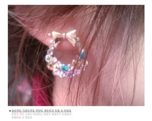 Detail of bow earrings with pink and blue rhinestones on ear for hypoallergenic wear