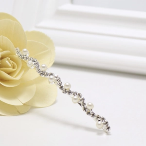 Gros plan sur la barrette en forme de S avec strass scintillants et perles blanches