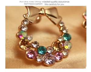 Macro detail of colorful rhinestone bow earrings featuring pink and teal crystals