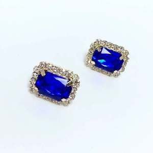 Close-up of vintage rectangular blue gemstone earrings with crystal halo and gold finish