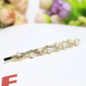 Vue détaillée de la pince à cheveux dorée ondulée avec perles et strass brillants
