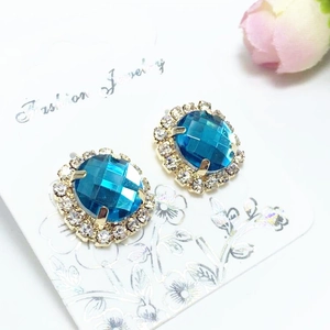 Détail de boucles d'oreilles rondes en cristal bleu foncé avec halo de strass blancs et or