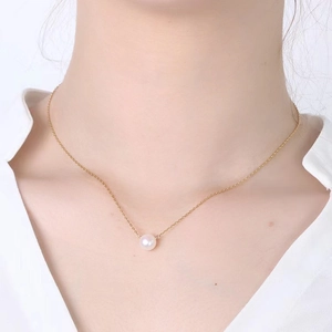 Élégant collier en chaîne dorée avec un pendentif perle blanche porté par un mannequin