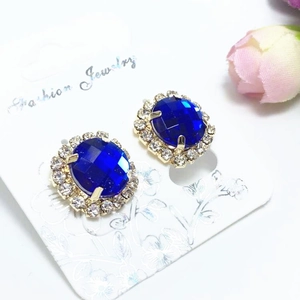 Gros plan de boucles d'oreilles ovales en cristal bleu avec halo sur carte de bijoux