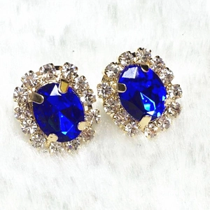 Close-up of vintage flower stud earrings with oval navy blue stone and crystal halo