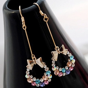 Elegant gold bow earrings with multi-colored crystal wreath drops on black ceramic display