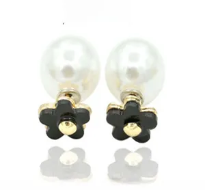 Detailed view of pearl stud earrings with black floral accents and gold center centers