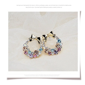 Elegant gold bow earrings with colorful rhinestone hoops on a soft white lace background