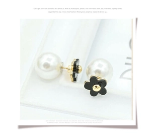Detail of elegant double-sided pearl earrings with black five-petal flower in gold finish