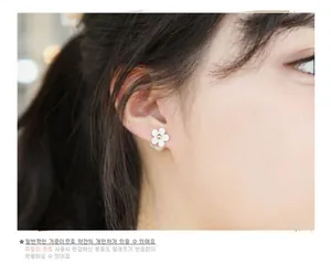 Detail of white flower stud earring with gold center pearl on a female model