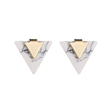 Detailed view of geometric triangle earrings with white marble texture and gold metal plates